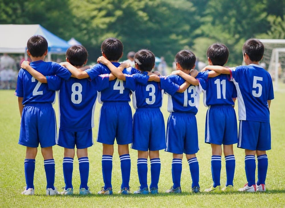 肩を組むスポーツチームの子どもたち
